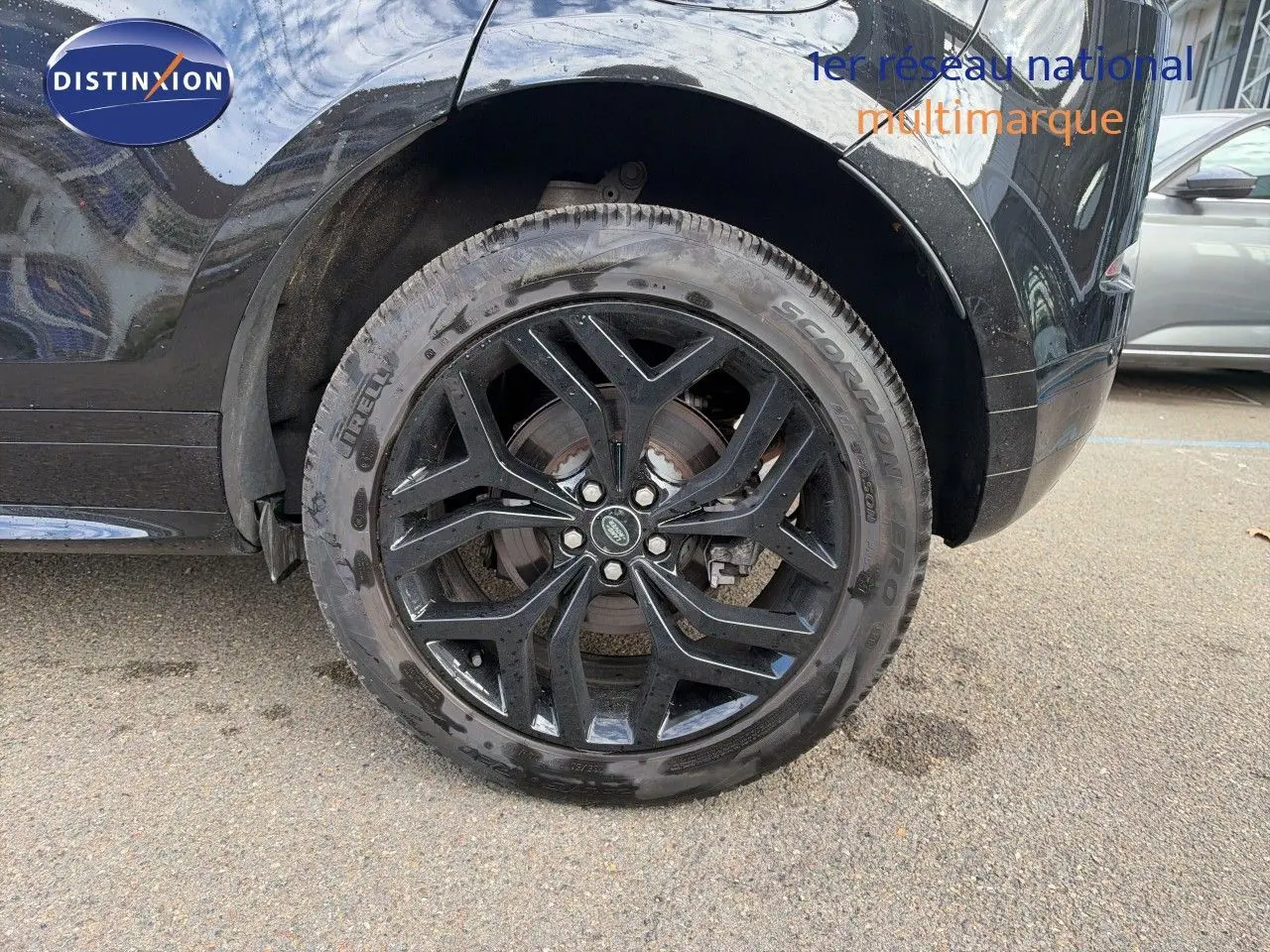Gros plan sur la roue arrière gauche noire brillante d’un Range Rover Evoque Santorini Black 2023, jante alliage noire.
