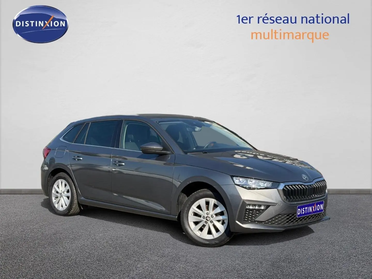 Skoda Scala gris en 3/4 avant droit, avec calandre chromée et jantes alu visibles sur fond neutre.