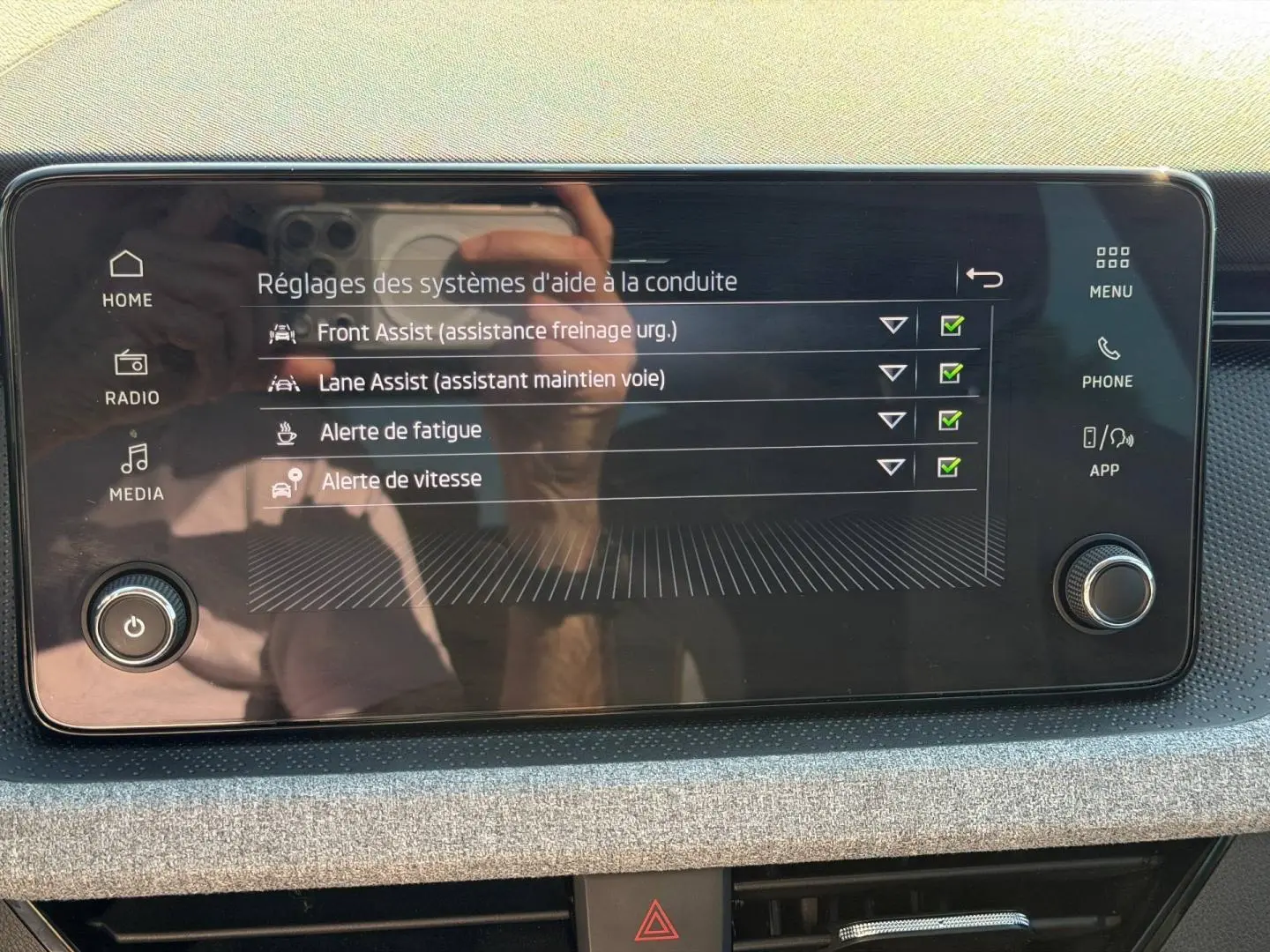 Écran tactile central du Skoda Scala 2025 montrant les réglages d’aide à la conduite, avec cadre noir et tableau de bord gris.