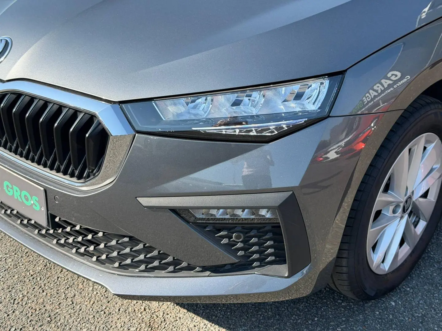 Gros plan sur l'avant droit gris métallisé d'une Skoda Scala 2025 avec calandre chromée et phares LED.