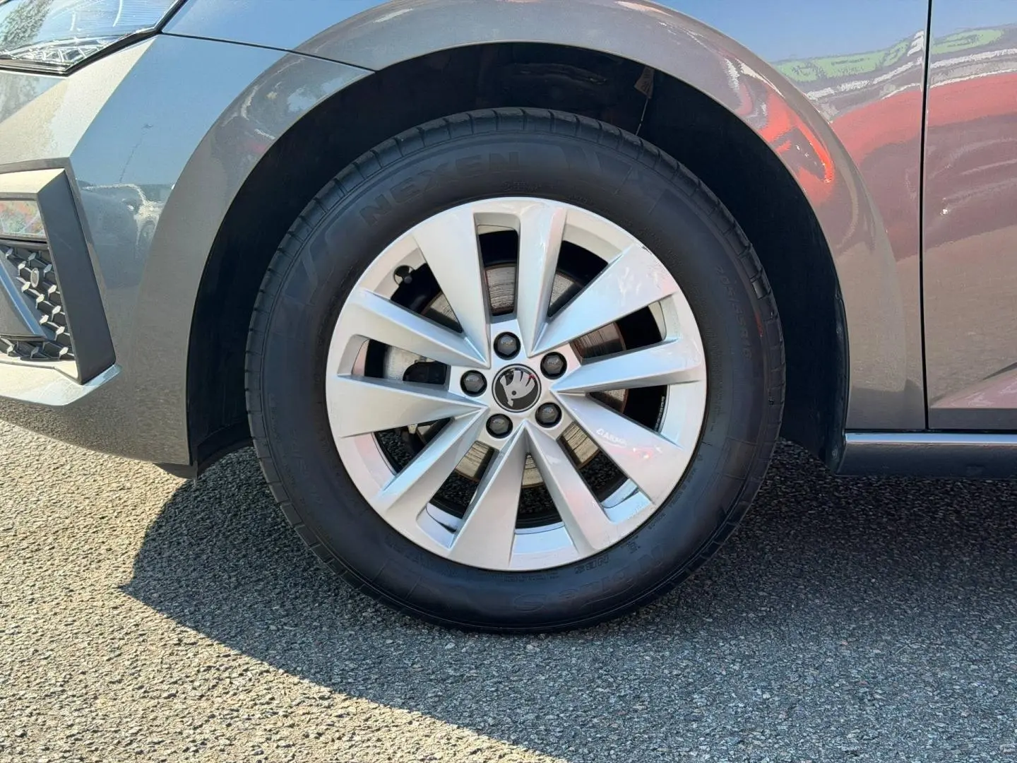 Gros plan sur la roue avant gauche gris métallisé d'une Skoda Scala avec jante alu et logo central visible.