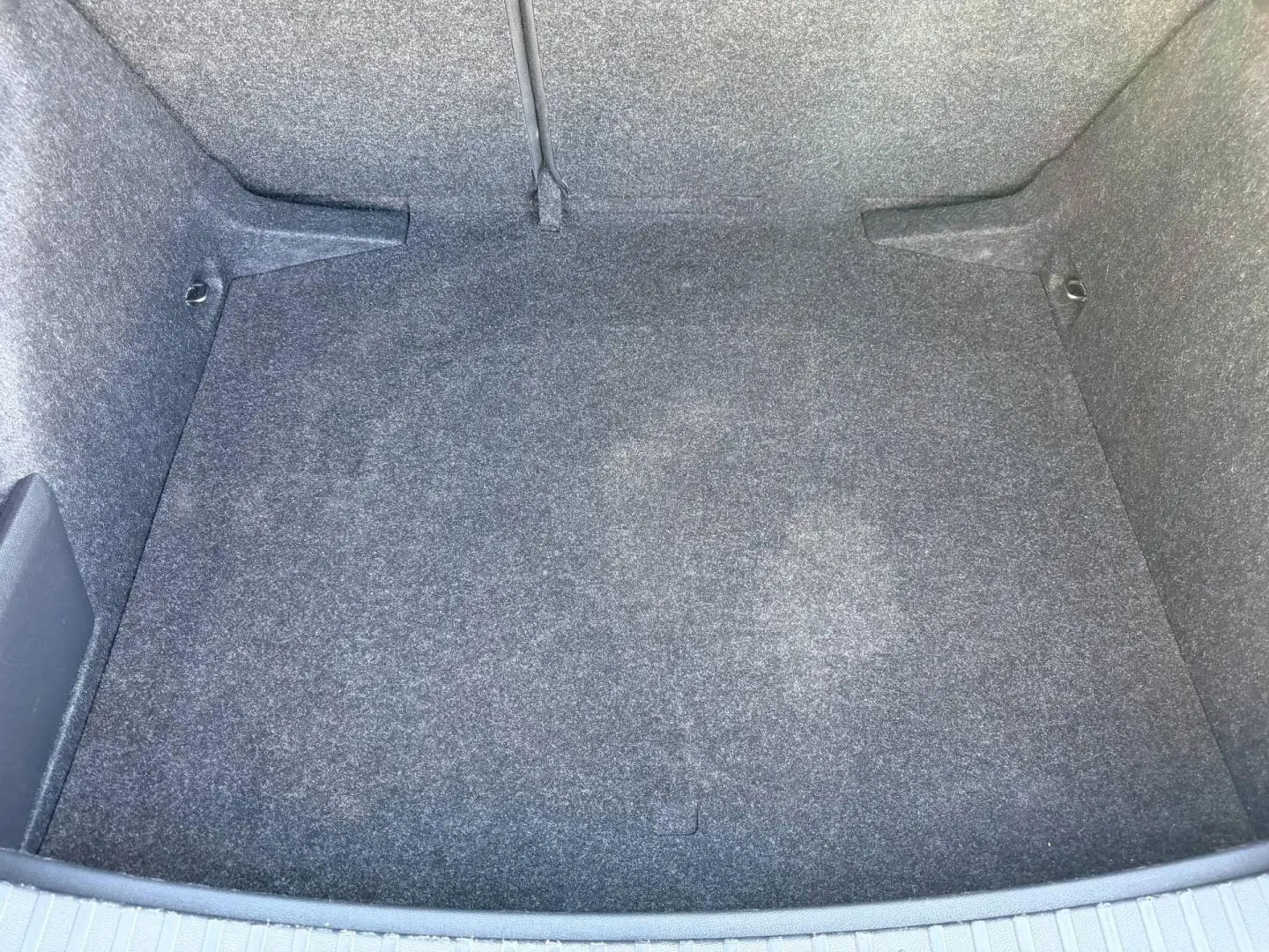 Coffre vide gris vu de dessus d'une Skoda Scala 2025, avec revêtement tissu et fixations Isofix visibles.