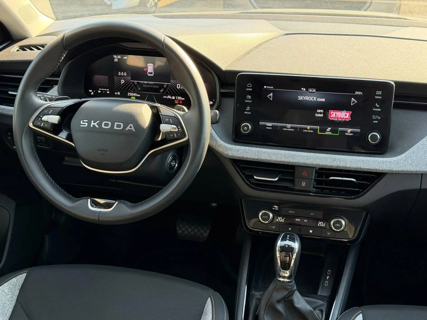 Vue intérieure frontale du poste de conduite gris d'une Skoda Scala 2025 avec écran tactile et volant multifonction.