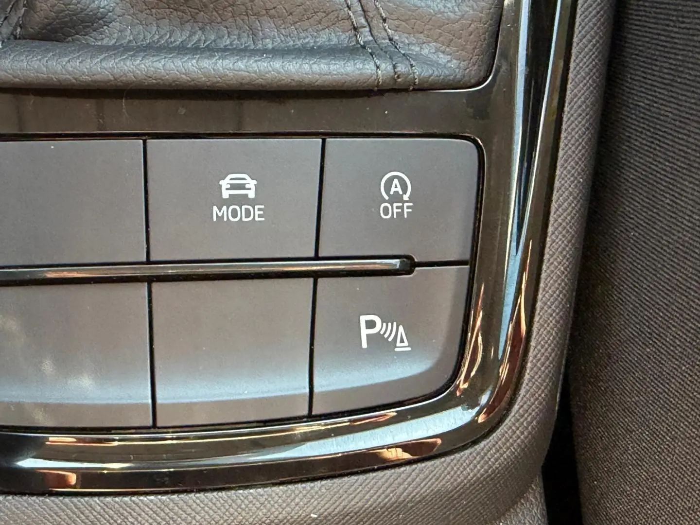Gros plan sur les commandes de mode de conduite et assistance au stationnement d'une Skoda Scala gris 2025.