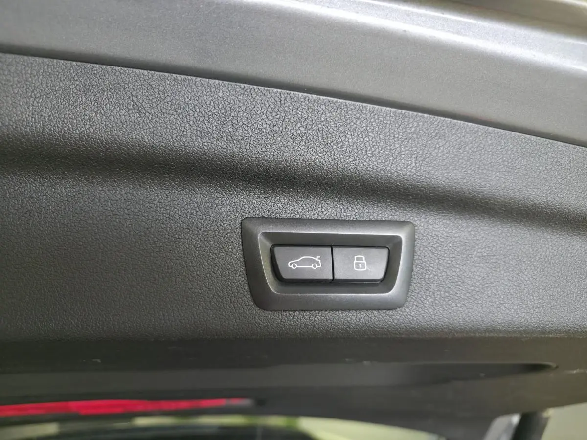 Boutons de commande du hayon et verrouillage intégrés au panneau intérieur du coffre d'une BMW Série 2 gris 3/4 arrière.