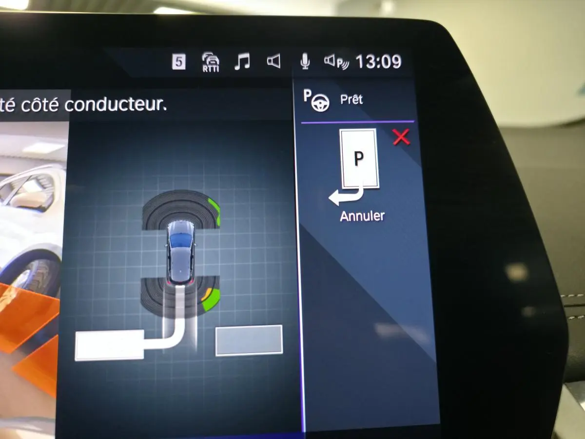 Écran tactile incurvé de la BMW Série 2 218i Active Tourer affichant l'aide au stationnement en vue de dessus du véhicule gris.