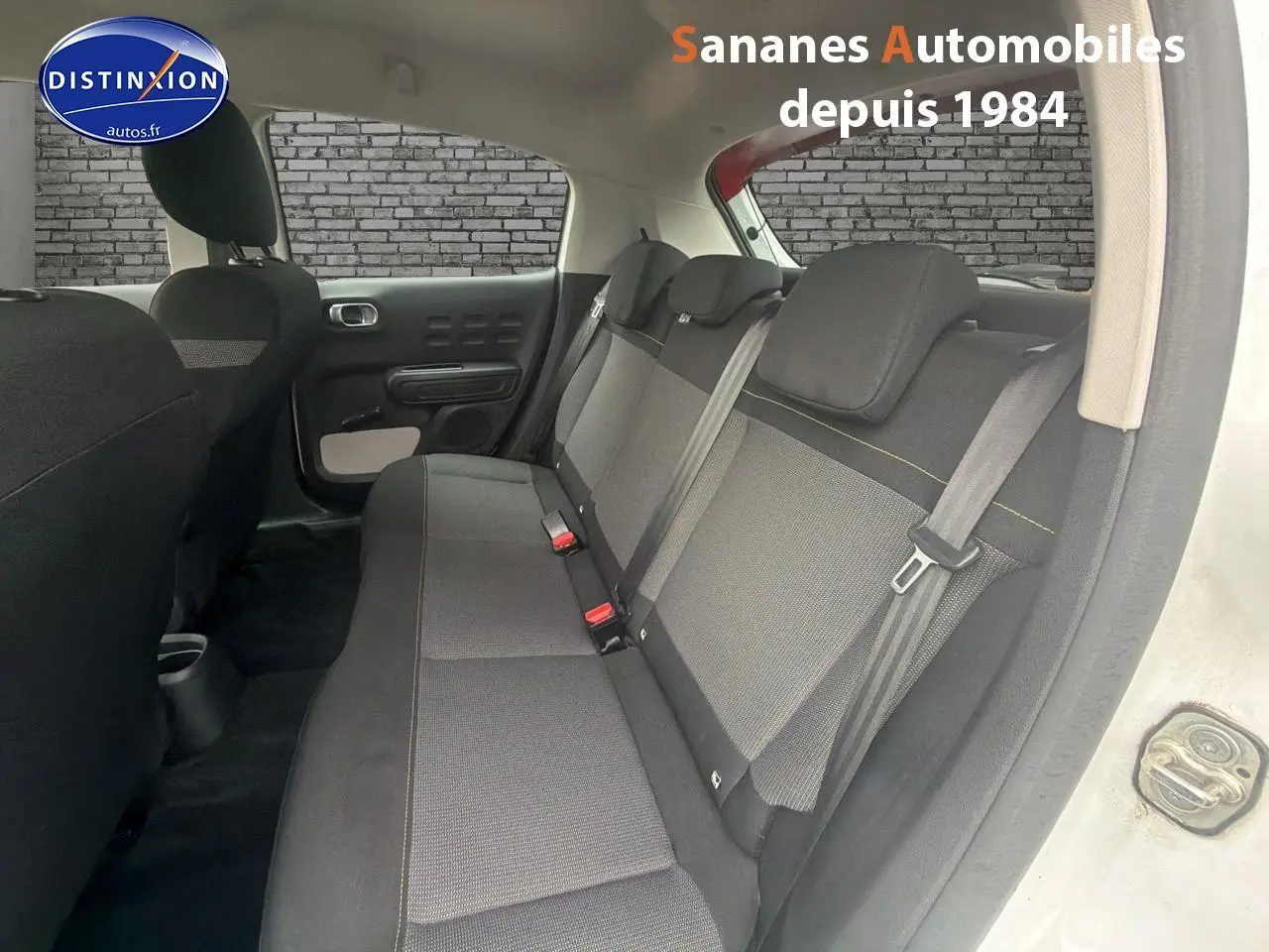 Vue intérieure côté droit montrant la banquette arrière en tissu gris et noir de la Citroën C3 blanc toit rouge.