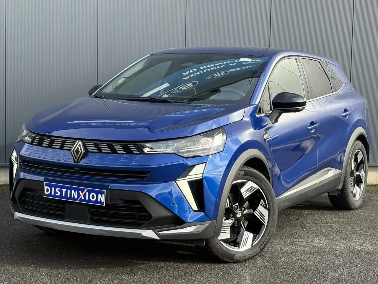 Renault Symbioz E-Tech bleu Iron en 3/4 avant droit, avec jantes 18 pouces et calandre distinctive noire.