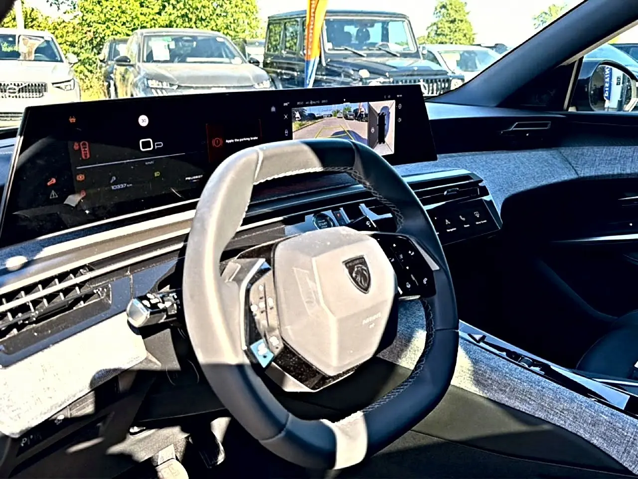 Intérieur du Peugeot 3008 2025 vu côté conducteur, volant cuir et grand écran tactile affichant caméra de recul.