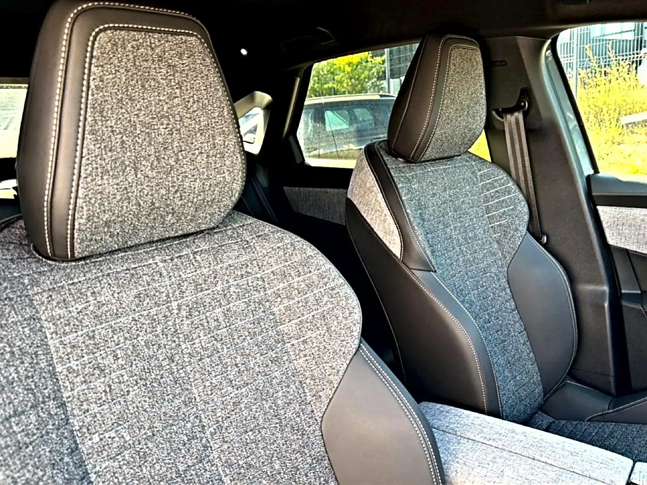 Gros plan sur les sièges avant en tissu gris et cuir noir du Peugeot 3008 1.2 hybrid 145 allure e-dcs6.