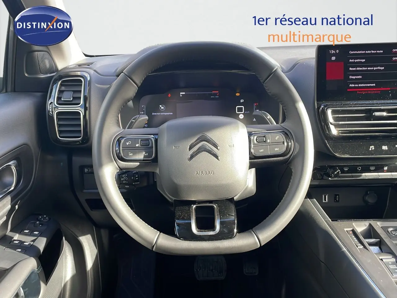 Vue intérieure centrée sur le volant cuir du Citroën C5 Aircross 2025 avec tableau de bord digital et écran tactile.