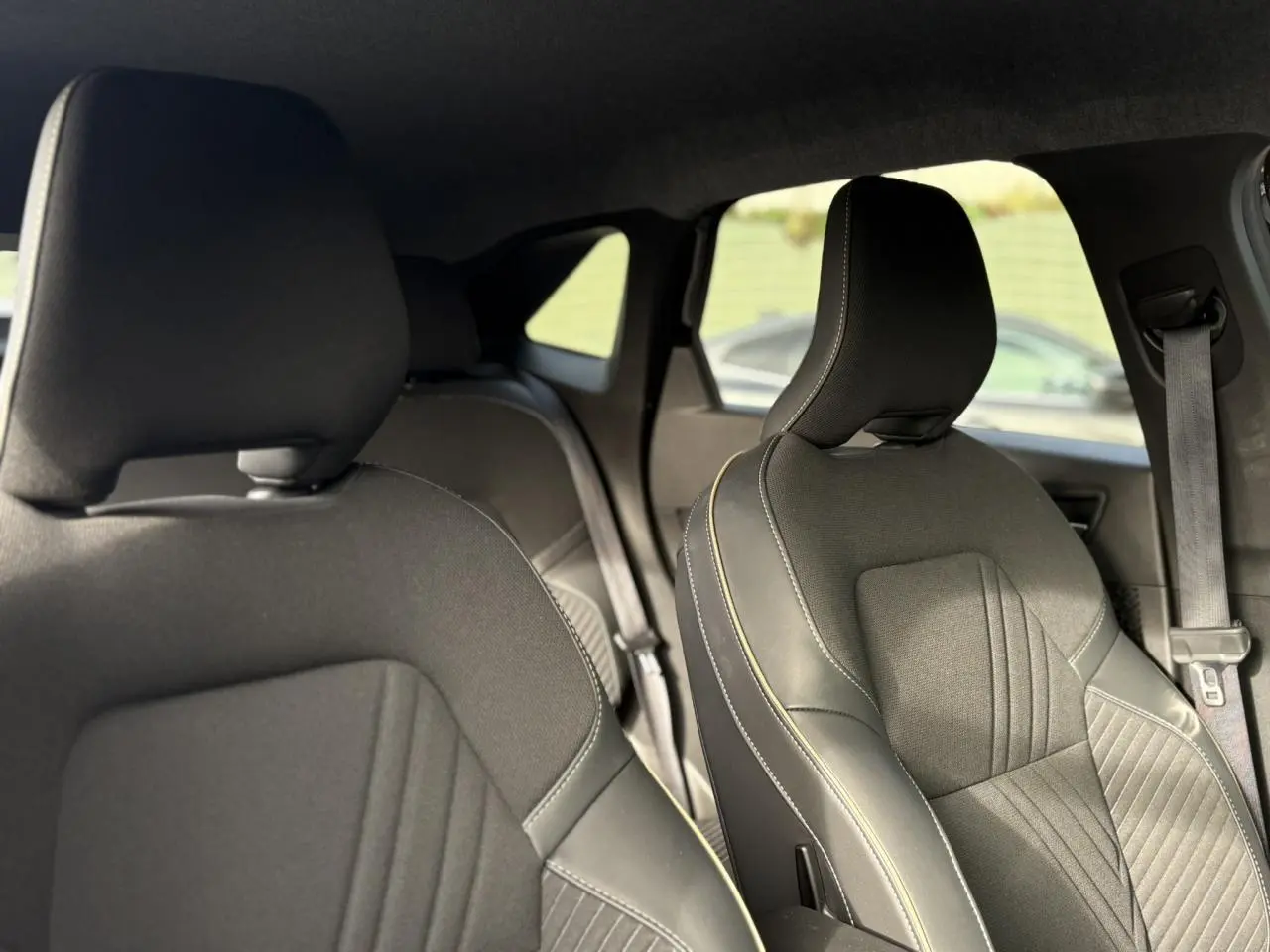 Vue intérieure des sièges avant en tissu noir avec surpiqûres contrastantes du Renault Symbioz E-Tech 2025.