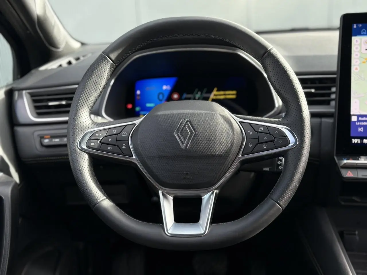 Vue rapprochée du volant noir perforé de la Renault SYMBIOZ 2025 avec commandes intégrées et tableau de bord numérique.