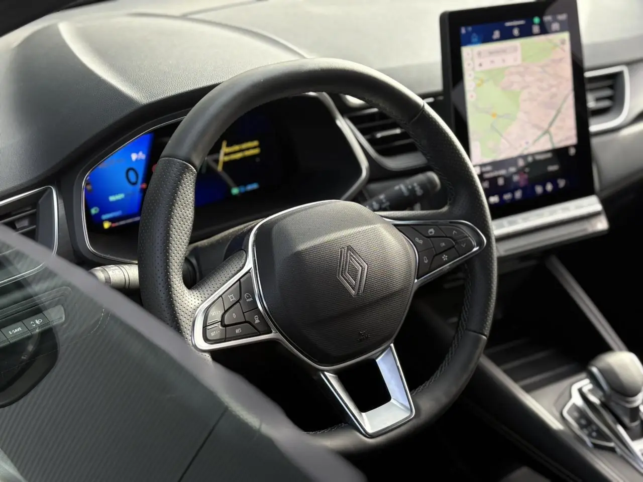 Vue intérieure centrée sur le volant noir perforé de la Renault Symbioz 2025 avec écran tactile vertical et tableau de bord numérique.
