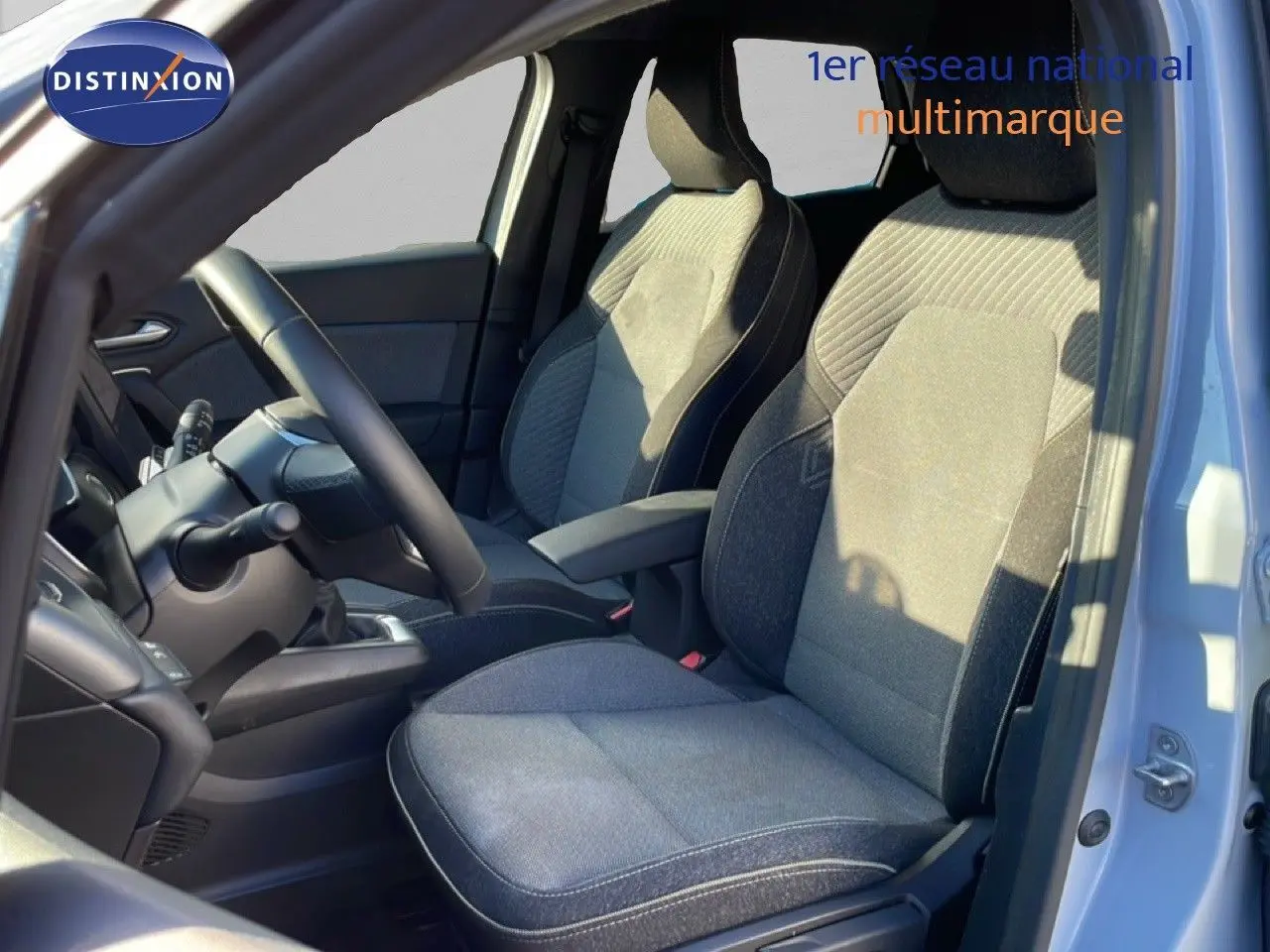 Vue intérieure côté conducteur du Renault Captur 2025, sièges tissu gris avec volant cuir noir visible.