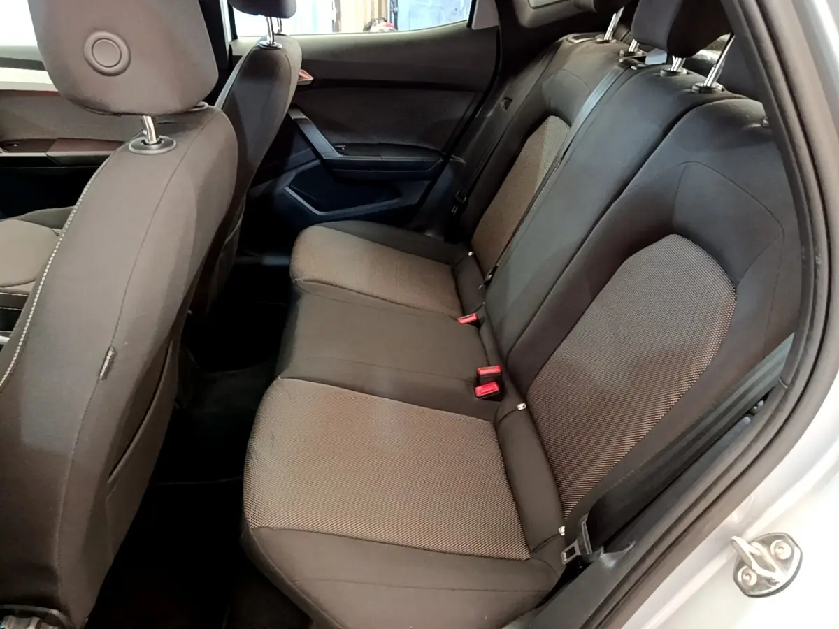 Vue intérieure côté droit sur la banquette arrière noire du SEAT Arona gris clair, avec ceintures et appuie-têtes visibles.