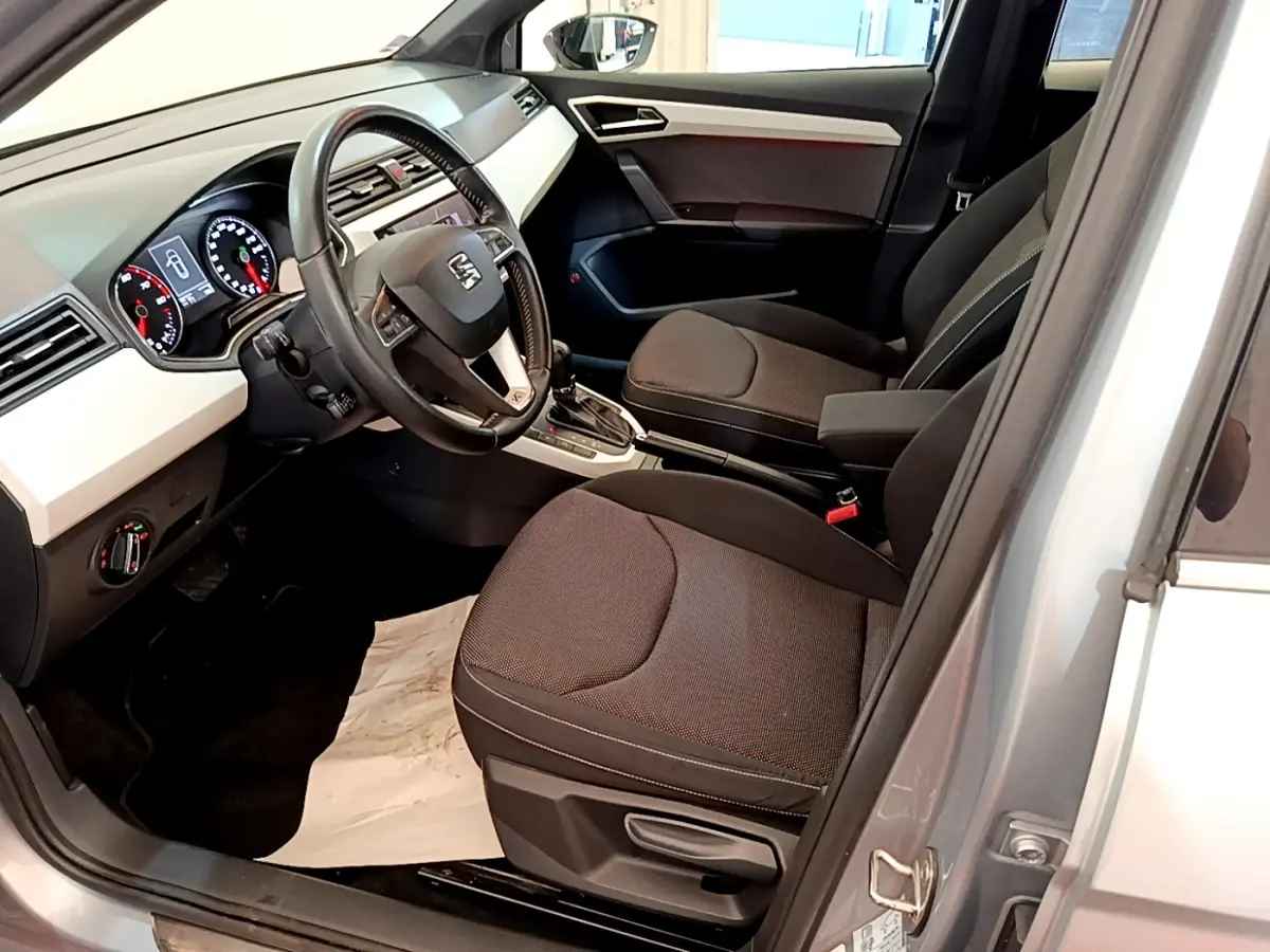 Intérieur avant droit d’un SEAT Arona gris clair 2019, volant cuir multifonctions et tableau de bord digital visible.