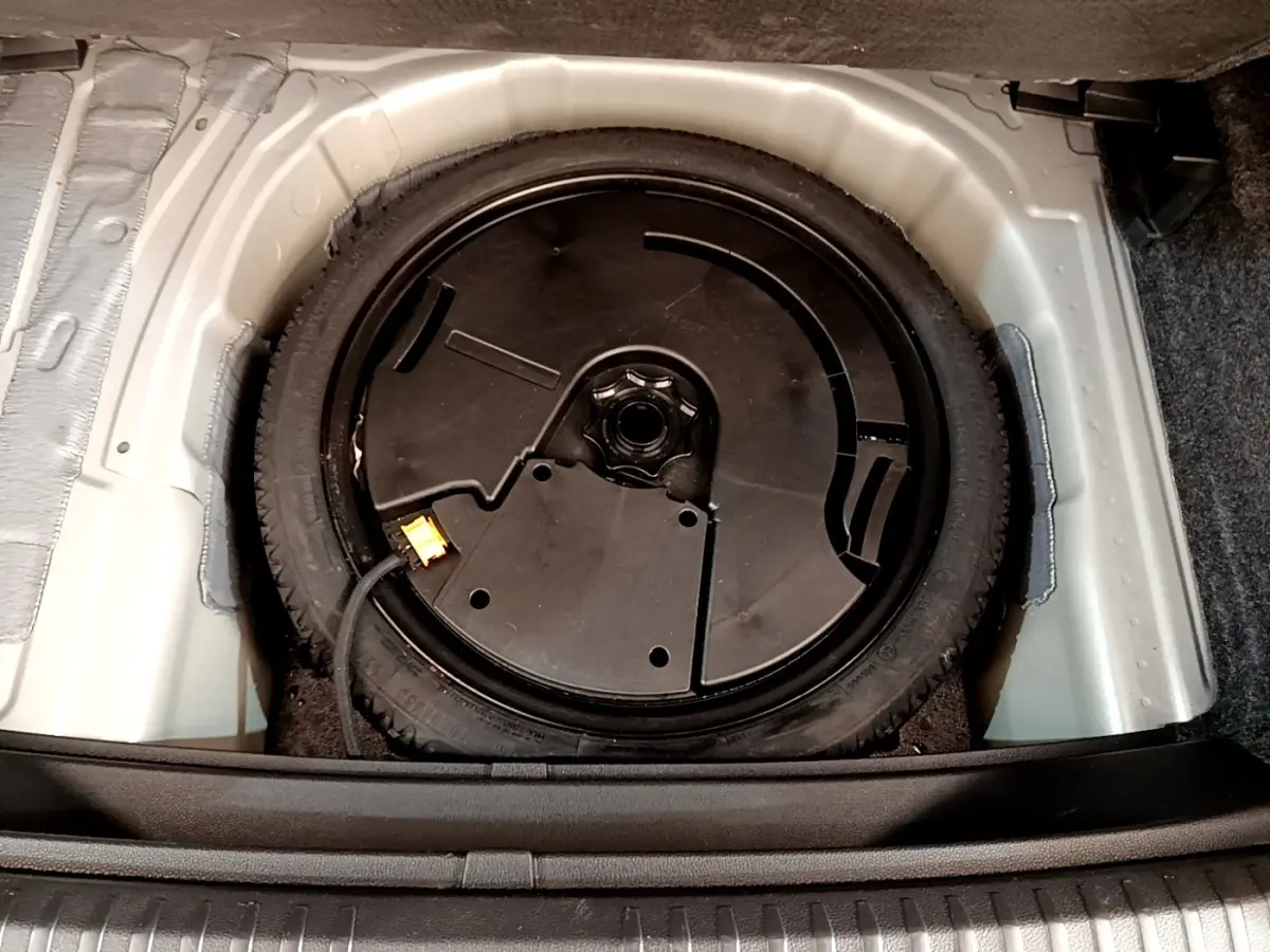 Vue plongeante sur la roue de secours noire dans le coffre d’un SEAT Arona gris clair de 2019.