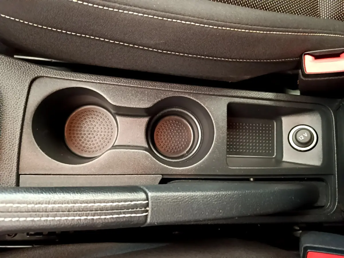 Vue rapprochée de la console centrale noire avec porte-gobelets et prise 12V du SEAT Arona gris clair 2019.