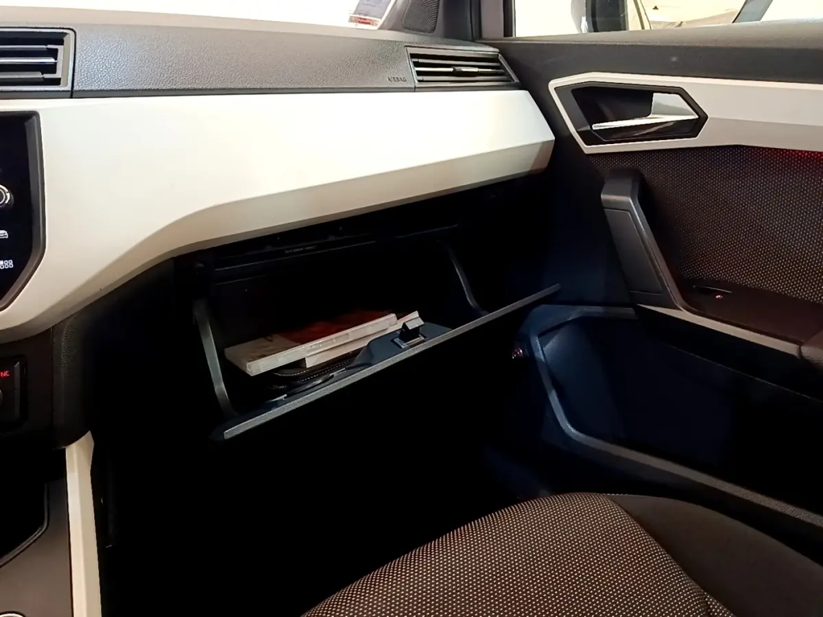 Vue intérieure côté passager du tableau de bord gris clair et boîte à gants ouverte du SEAT Arona 2019.