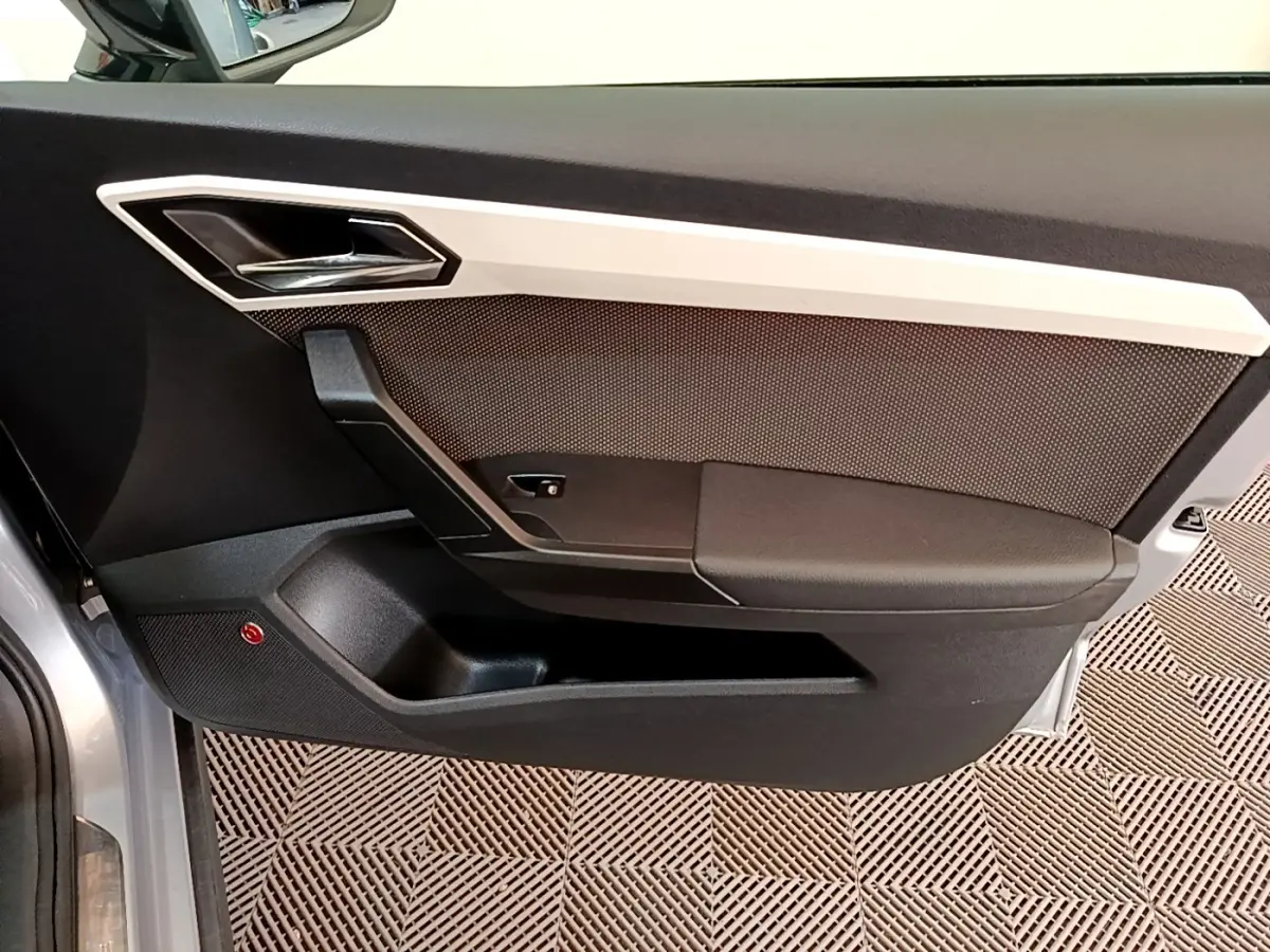 Vue intérieure côté gauche de la porte avant gris clair du SEAT Arona avec garniture noire et insert argenté.