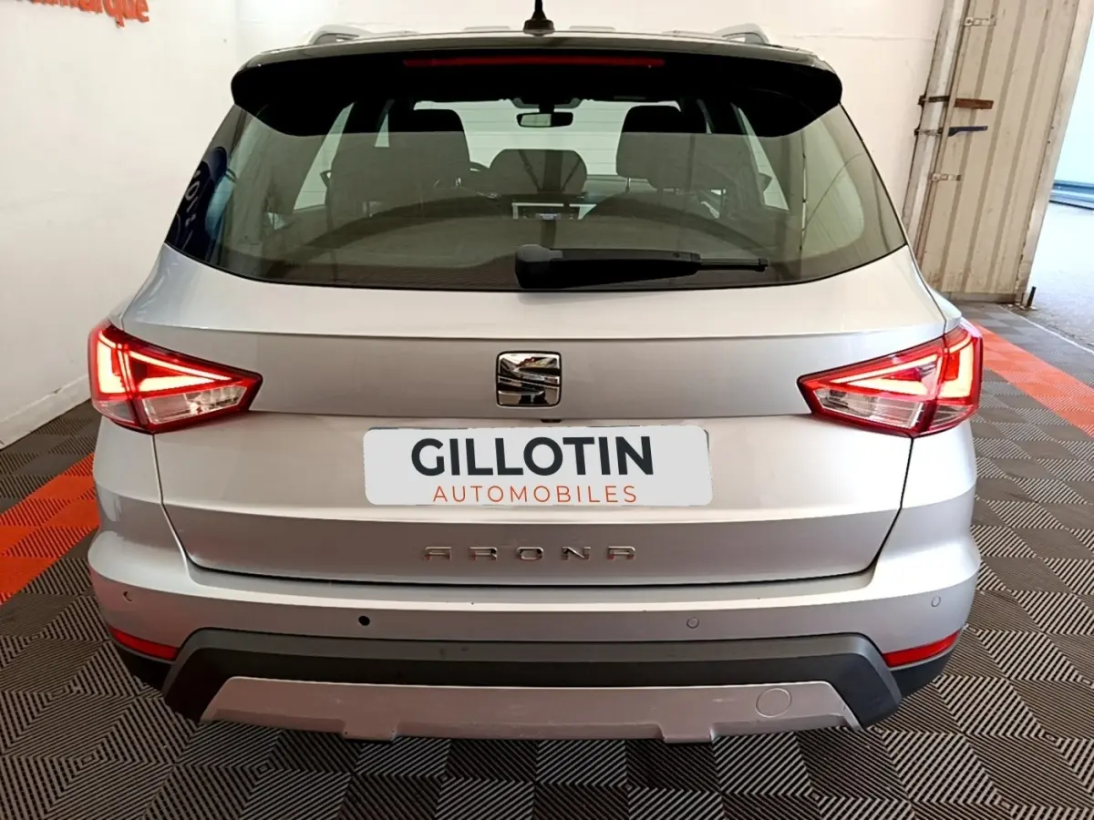 Vue arrière d'un SEAT Arona gris clair 2019 avec feux LED allumés et logo central visible.