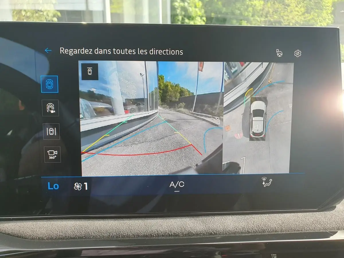 Écran intérieur montrant l’aide au parking 360° de la Renault Clio VI gris Rafale avec vue arrière et vue aérienne du véhicule.