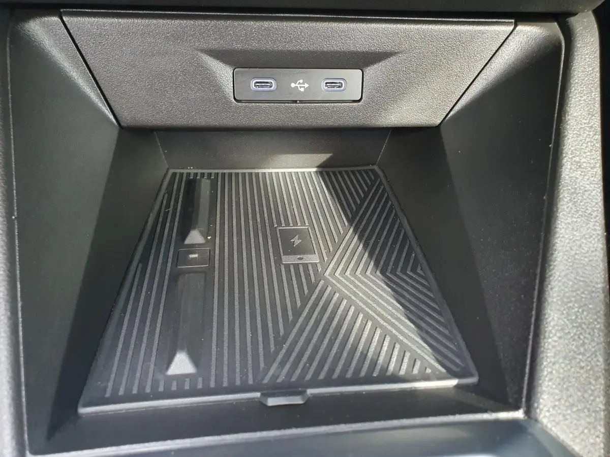 Gros plan sur la zone de rangement avant noire avec deux prises USB-C éclairées dans une Renault Clio VI gris Rafale.