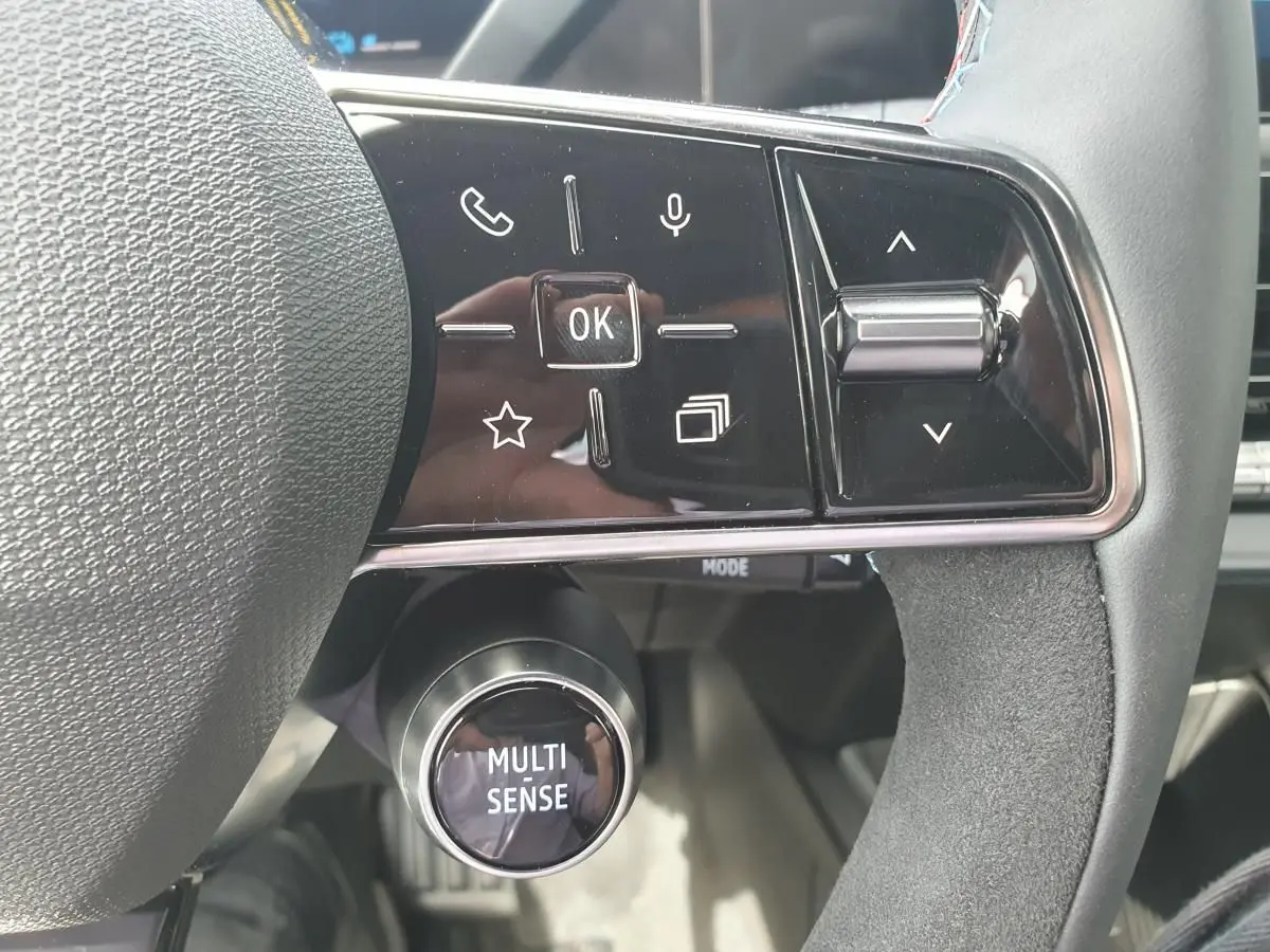 Gros plan sur les commandes au volant de la Renault Clio VI gris Rafale, avec bouton Multi-Sense et touches multifonctions.