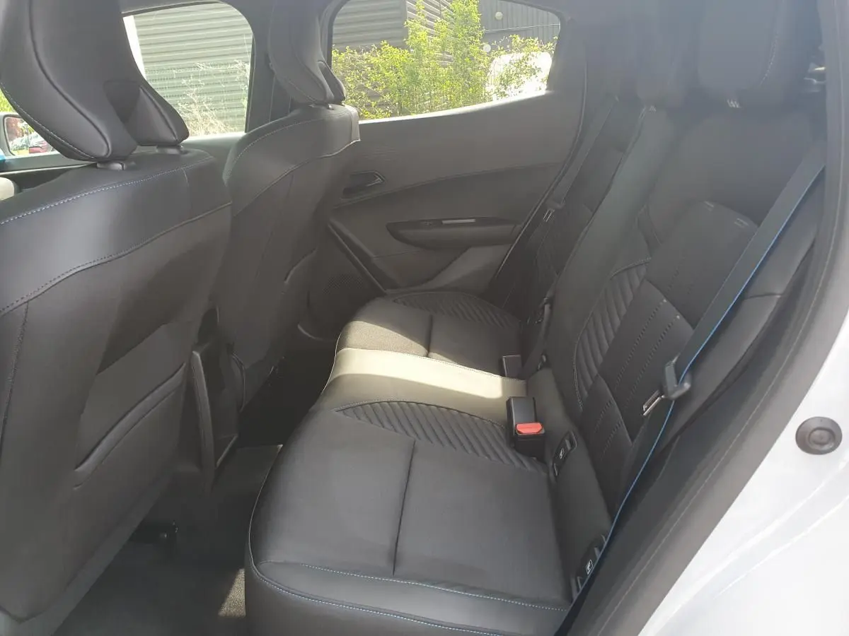 Vue intérieure côté droit des sièges arrière en tissu noir avec surpiqûres bleues d'une Renault Clio VI gris Rafale.