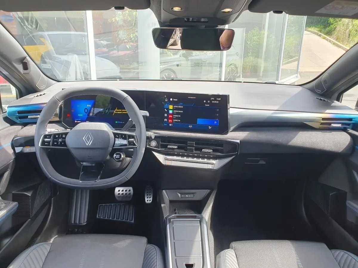 Vue frontale de l’habitacle de la Renault Clio VI gris Rafale, avec tableau de bord numérique et volant multifonctions.