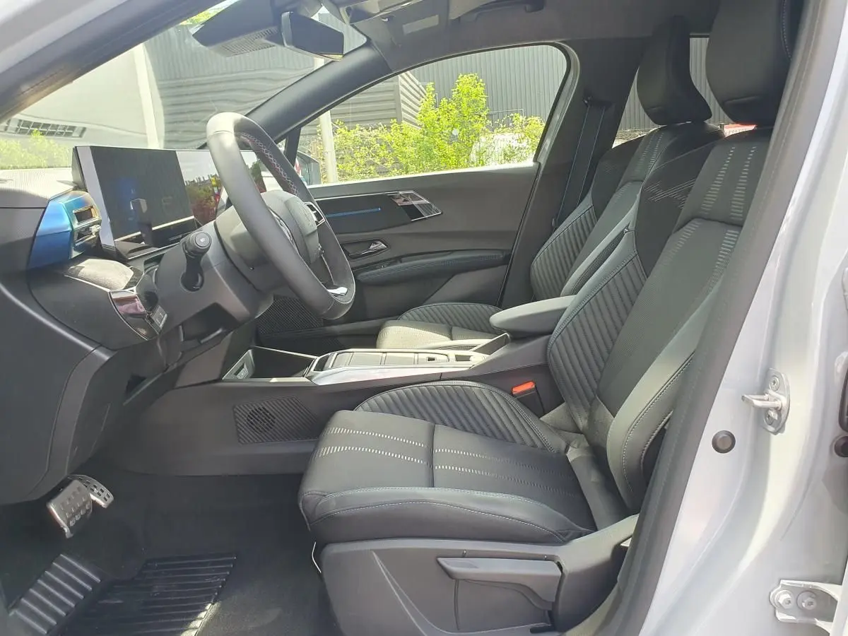 Vue intérieure côté conducteur de la Renault Clio VI gris Rafale, avec sièges en tissu noir et tableau de bord moderne.