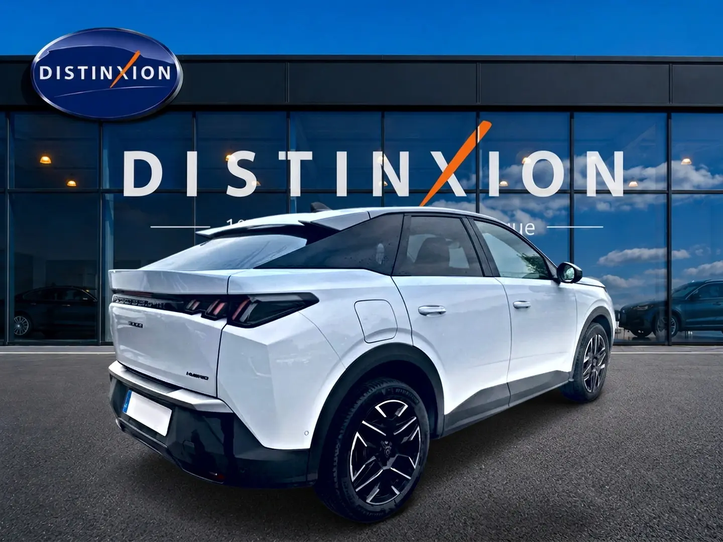 Vue 3/4 arrière droite d'un Peugeot 3008 blanc avec jantes alu noires devant une vitrine Distinxion.