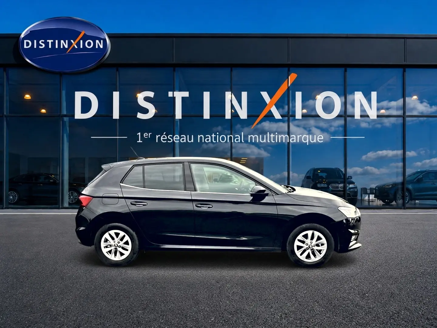 Profil droit d'une Skoda Fabia noire 2025 garée devant une vitrine avec logo Distinxion.