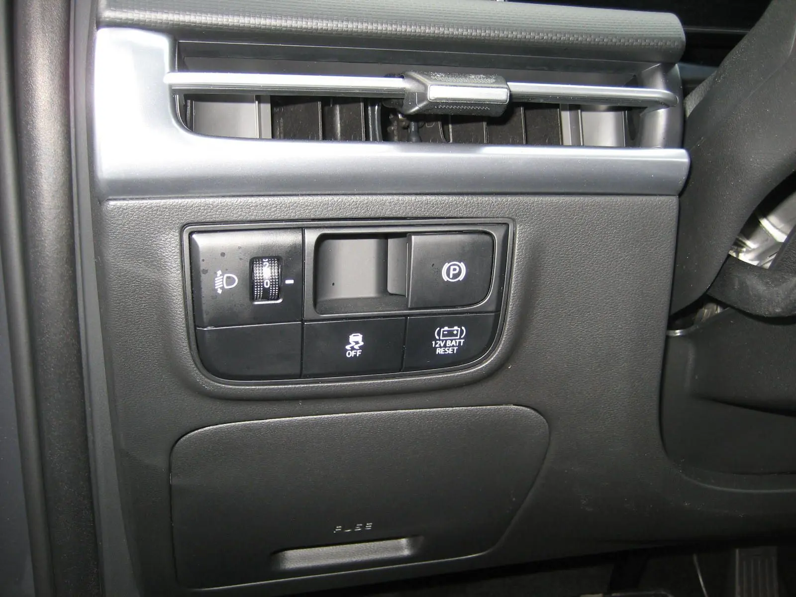 Vue rapprochée du tableau de bord côté gauche du Hyundai Tucson 2025 gris Ecotronic, montrant les commandes d'éclairage et frein à main électrique.