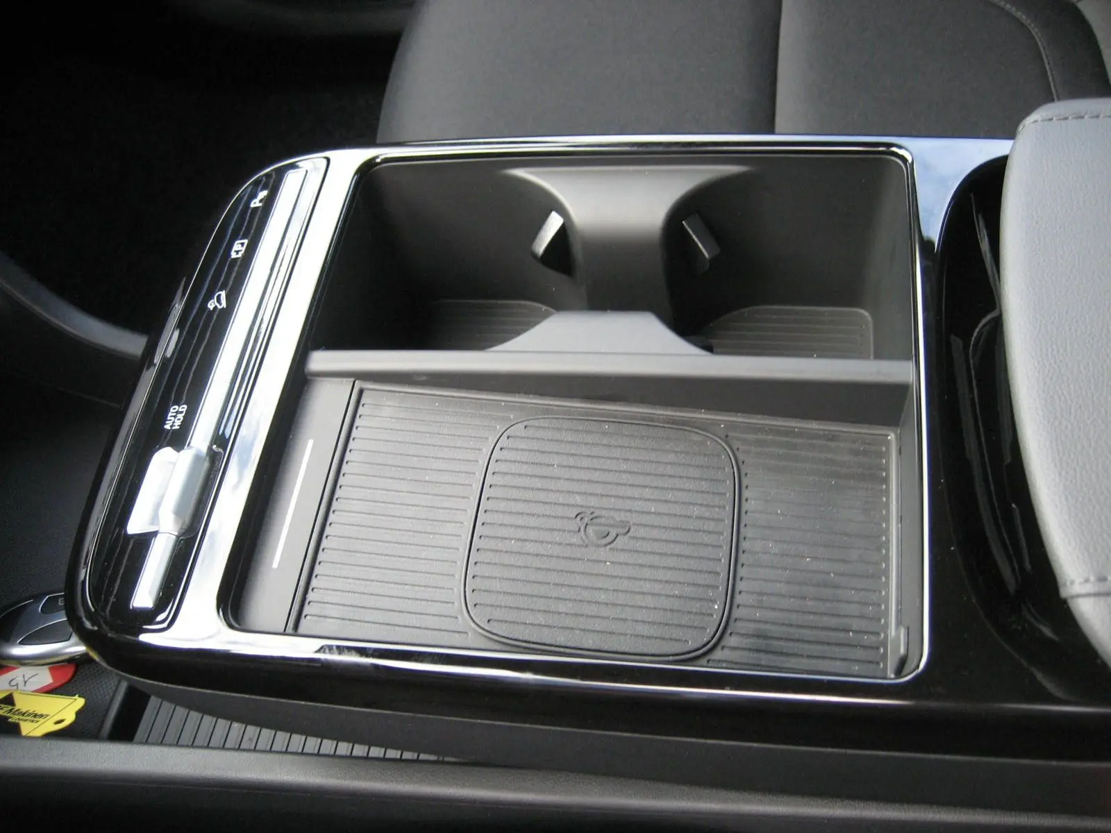 Gros plan sur la console centrale noire du Hyundai Tucson 2025 avec plateau de recharge sans fil et porte-gobelets.