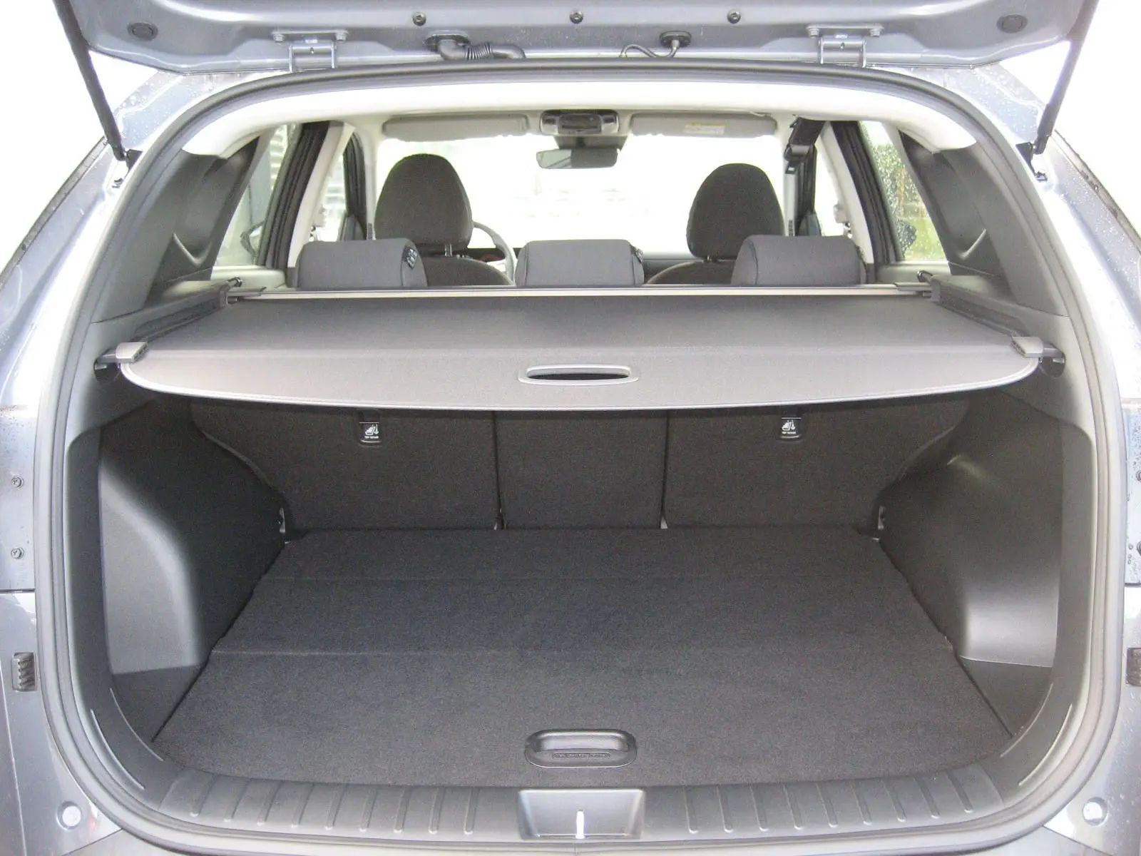 Coffre ouvert d'un Hyundai Tucson 2025 gris Ecotronic, vue arrière montrant la plage arrière et les sièges arrière.