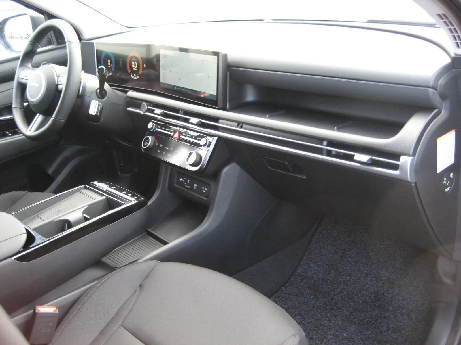 Vue intérieure côté passager du Hyundai Tucson 2025 gris Ecotronic, tableau de bord moderne avec écran tactile panoramique.