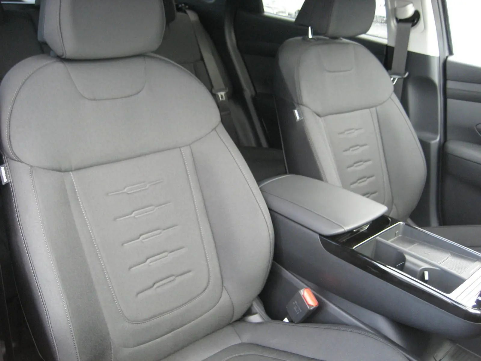 Gros plan sur les sièges avant gris du Hyundai Tucson 2025, finition Style, avec accoudoir central et console épurée.