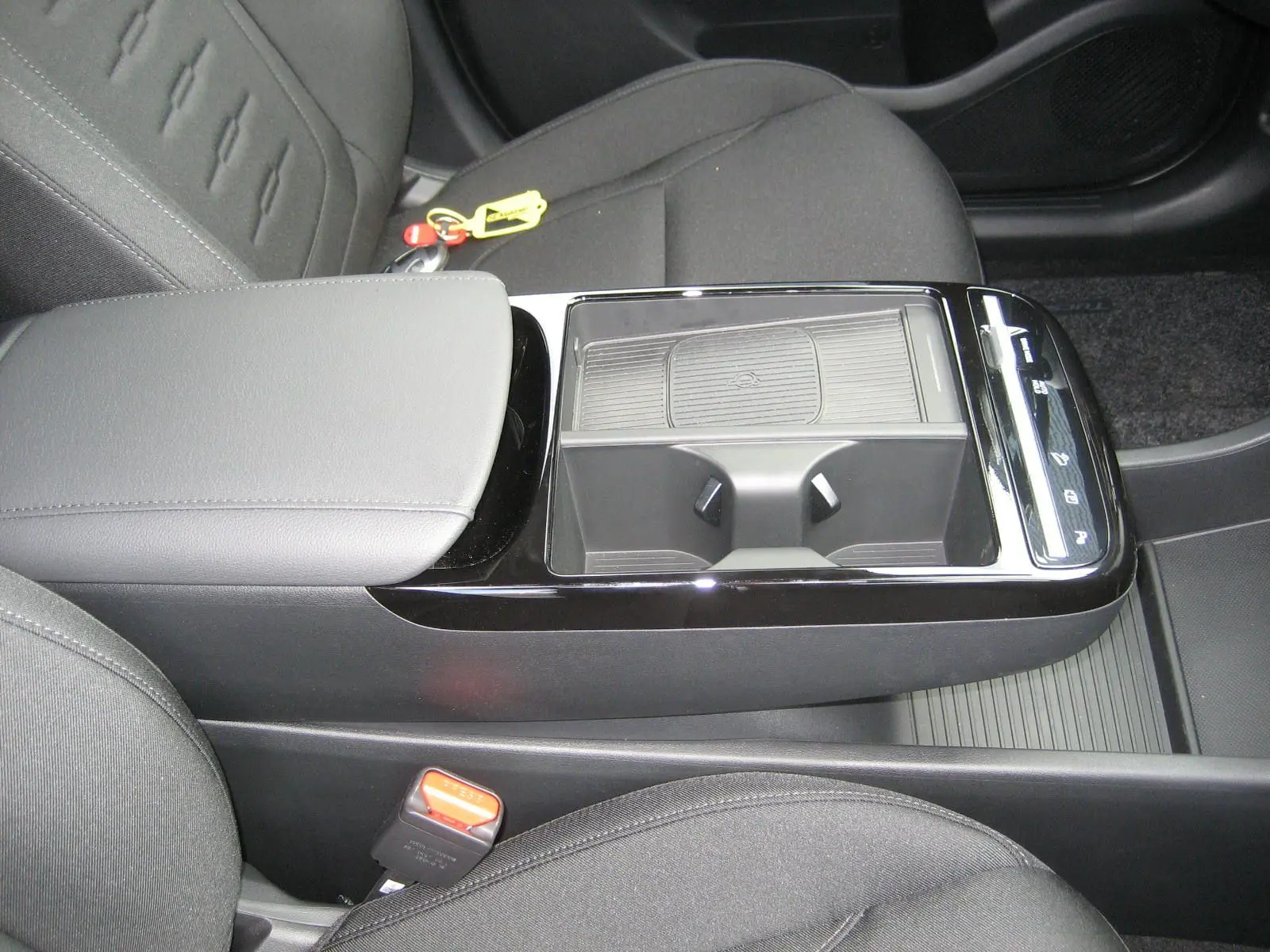 Vue rapprochée de la console centrale noire et grise du Hyundai Tucson 2025, avec porte-gobelets et accoudoir en tissu.