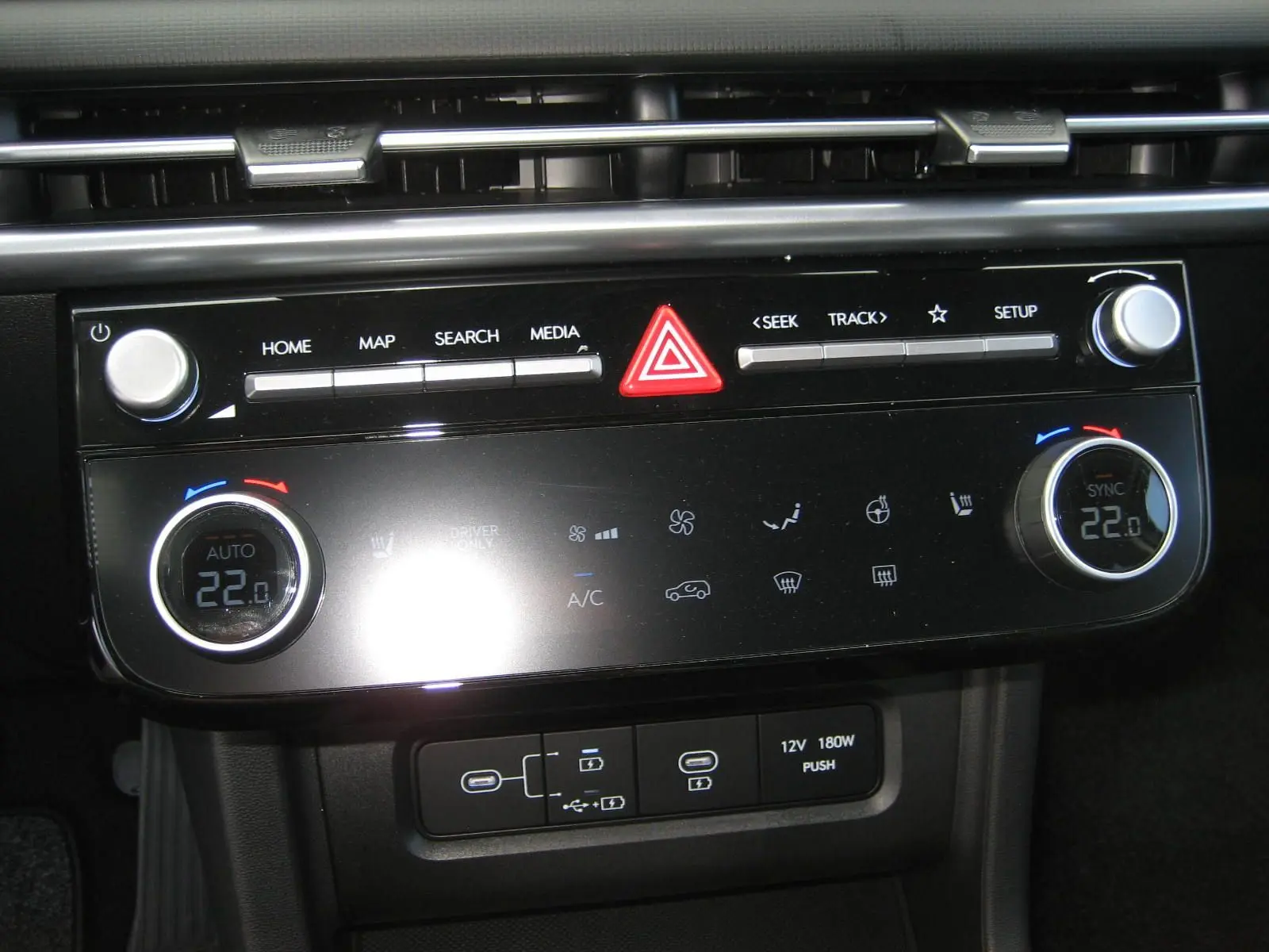 Tableau de bord du Hyundai Tucson 2025 en gris, montrant la console centrale avec commandes climatisation et multimédia.