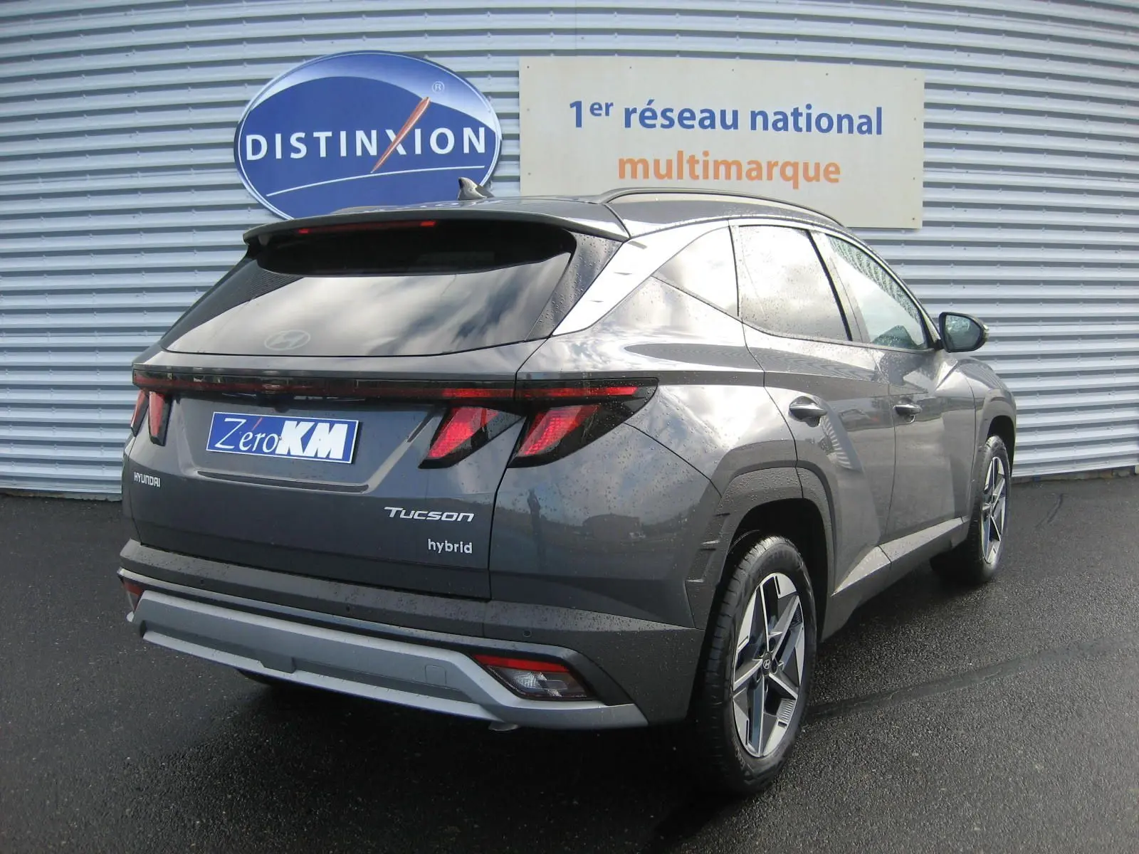 Vue 3/4 arrière droite du Hyundai Tucson 2025 hybride en gris Ecotronic, avec feux arrière LED et jantes alliage distinctives.