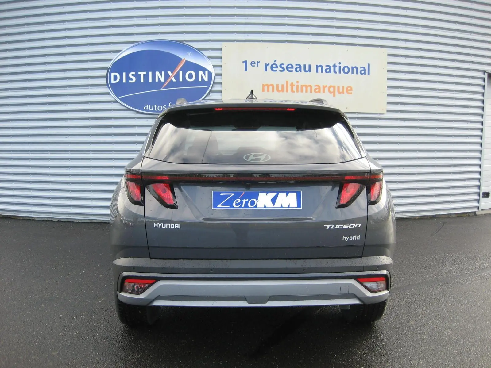 Vue arrière d'un Hyundai Tucson hybride 2025 en gris Ecotronic, avec feux arrière LED et logo "hybrid" visible.