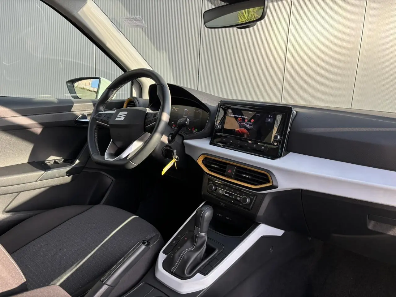 Vue intérieure côté conducteur du SEAT Arona blanc 2025, avec tableau de bord moderne et écran tactile central.