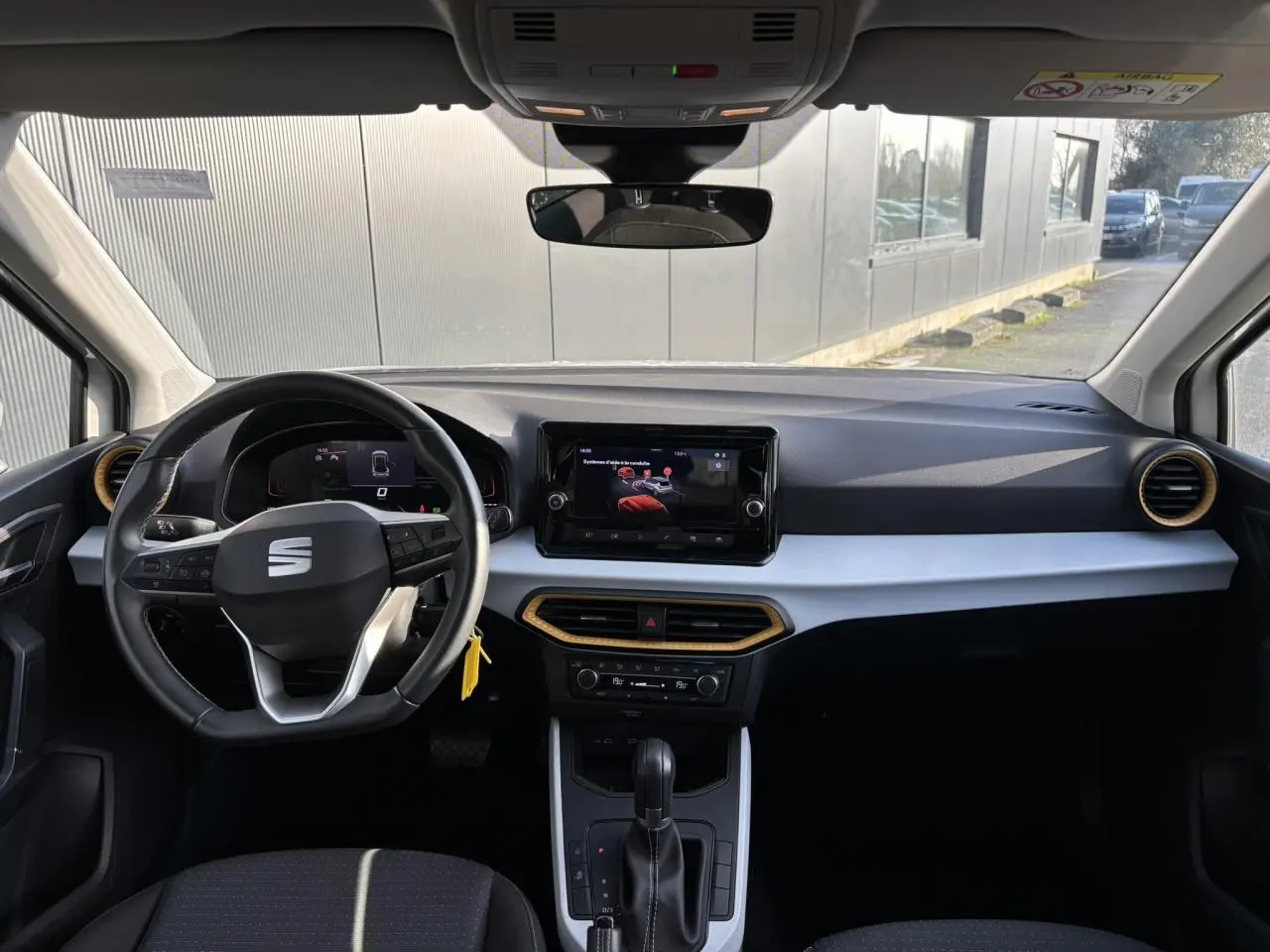 Vue intérieure avant du tableau de bord du SEAT Arona blanc, avec volant multifonction et écran tactile central.