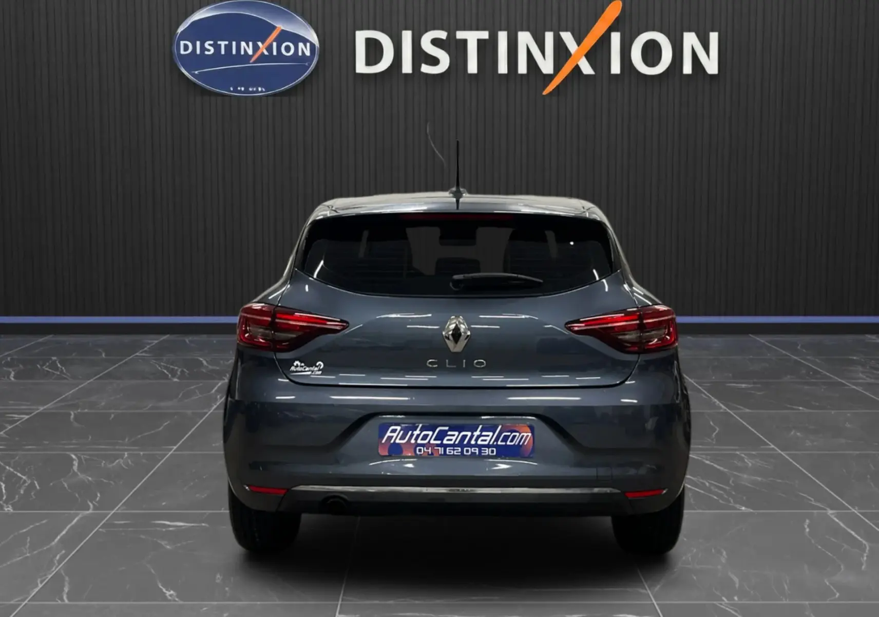 Vue arrière d'une Renault Clio V Business gris titanium de 2019, avec logo et feux arrière distinctifs visibles.