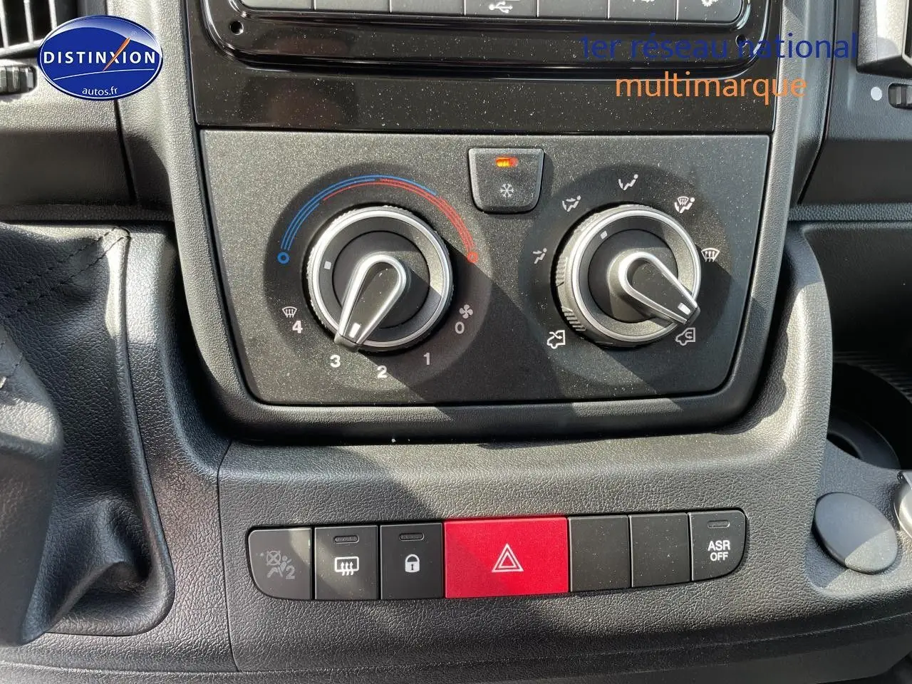 Gros plan sur la console centrale du Peugeot Boxer Fourgon 2023, montrant les commandes de climatisation et les boutons de sécurité.