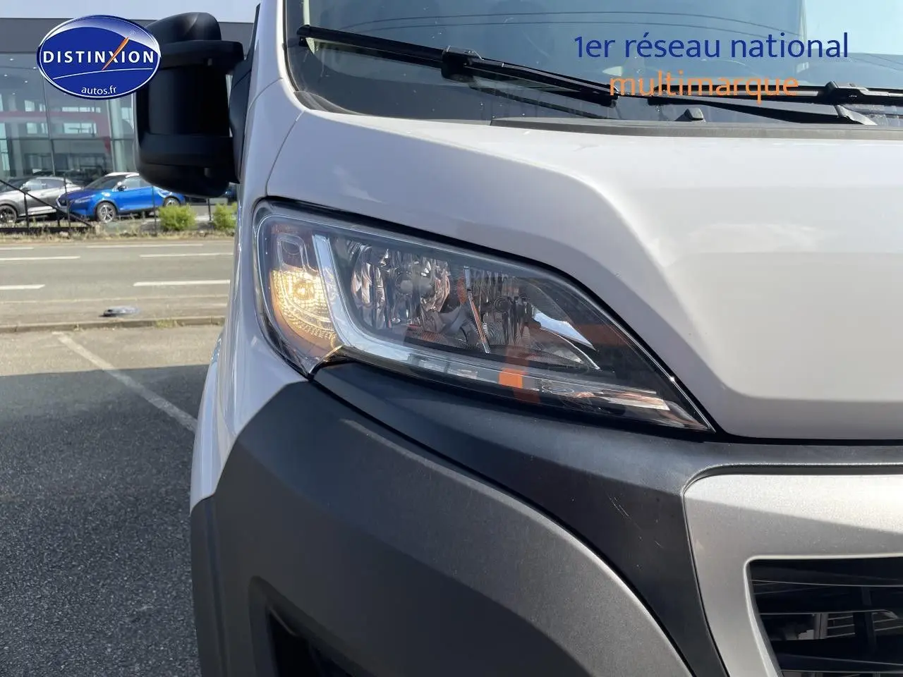 Gros plan sur le phare avant gauche allumé du Peugeot Boxer Fourgon blanc, avec pare-chocs noir visible.