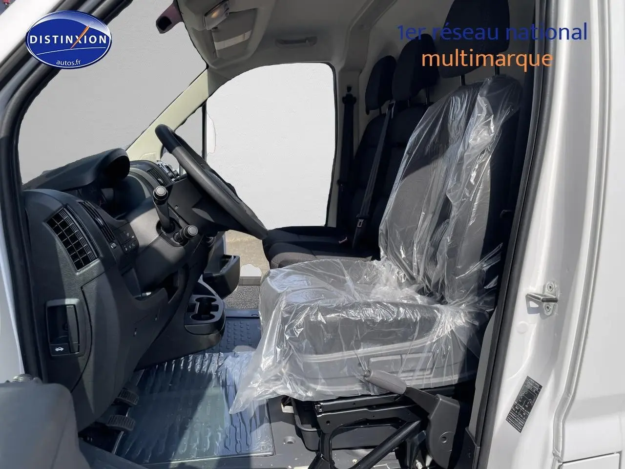 Intérieur côté conducteur du Peugeot Boxer Fourgon blanc 2023, sièges avant protégés par film plastique.