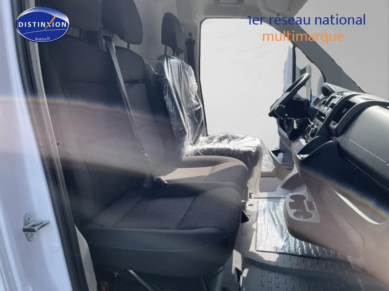 Vue intérieure côté gauche du Peugeot Boxer Fourgon blanc 2023, montrant les sièges avant en tissu noir et le tableau de bord.